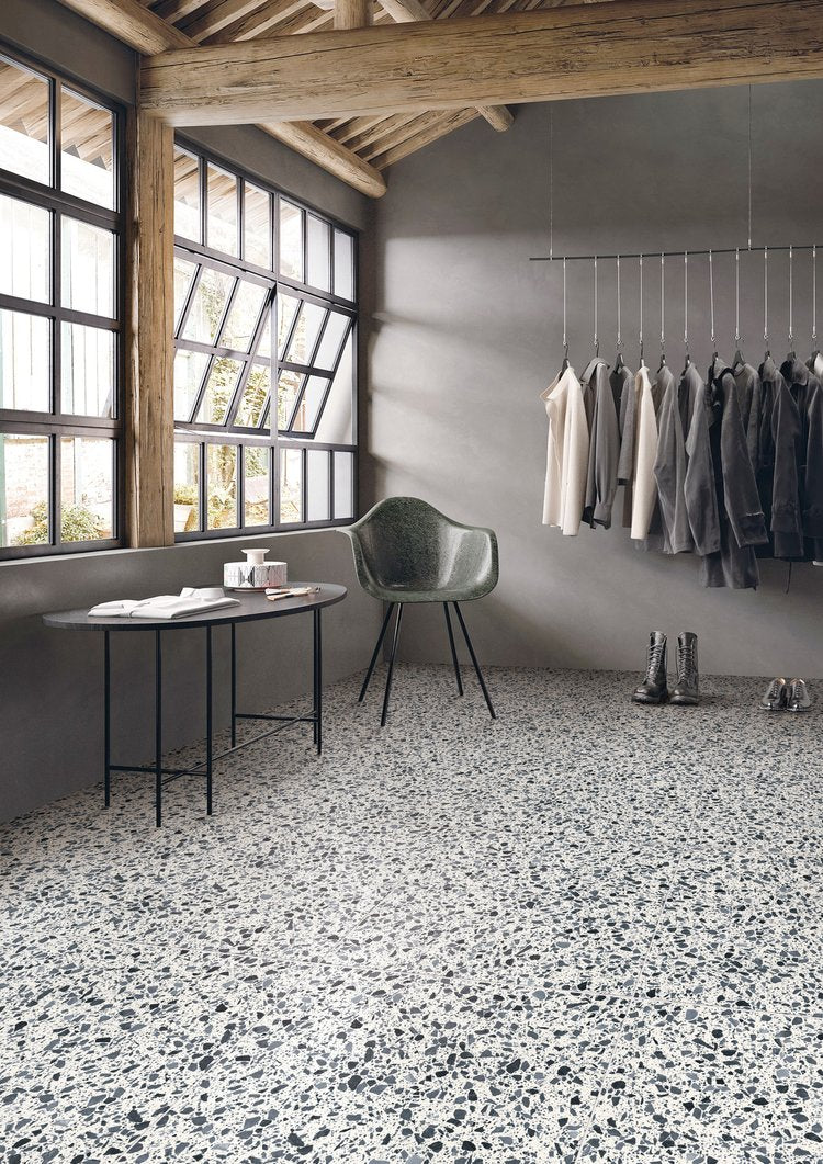 Modern interior with terrazzo flooring, gray walls, and a clothing rack.